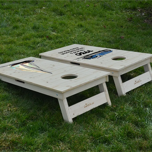 cornhole 2 planches motifs personnalisables sur fond de bois naturel, sur le gazon, vue de derrière