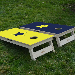 cornhole 2 planches étoile jaune et étoile bleue sur fonds inversés, sur le gazon, vue de derrière