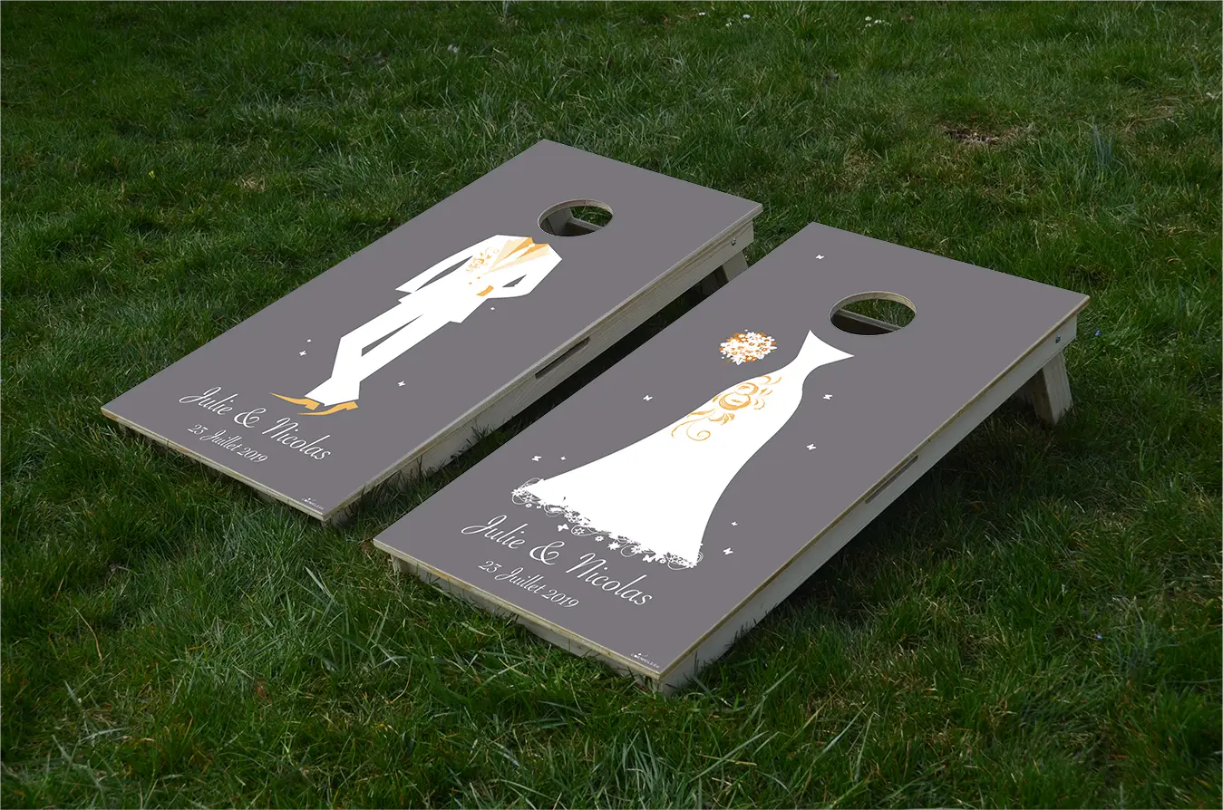 cornhole 2 planches marié et mariée, avec inscription de leurs prénoms et de la date de leur mariage, sur le gazon, vue de face
