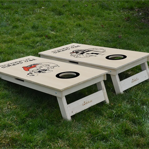 cornhole de compétition deux planches tête de mort et hipster, sur le gazon, vue de derrière