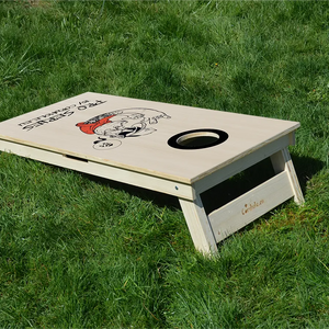 cornhole Pro de compétition hipster tatoué, sur le gazon, vue de derrière