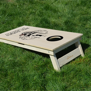 cornhole Pro de compétition tête de mort en train de fumer un cigare, sur le gazon, vue de derrière