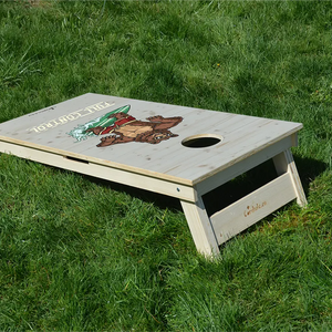 cornhole ours en short de bain sur une planche de surf, sur le gazon, vue de derrière