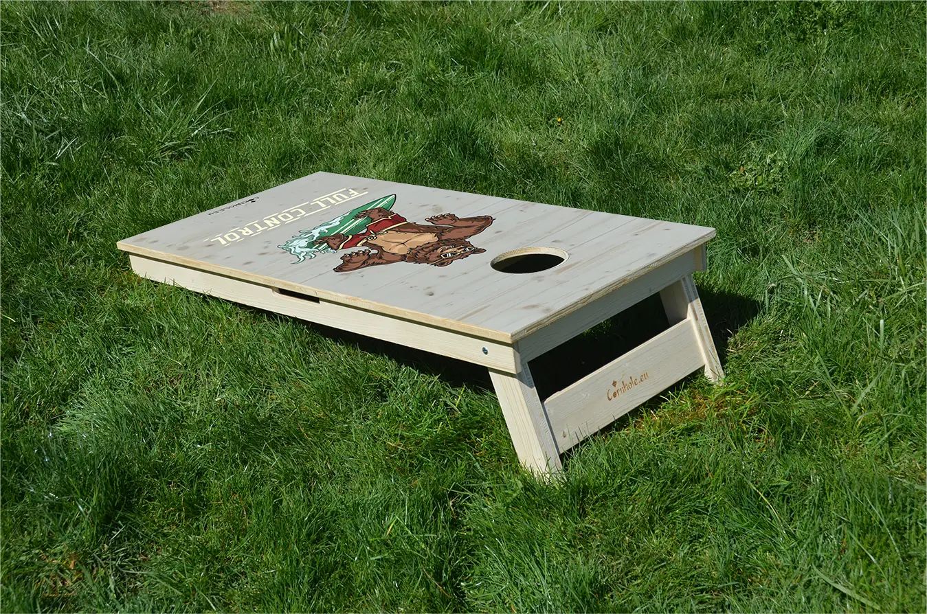 cornhole ours en short de bain sur une planche de surf, sur le gazon, vue de derrière