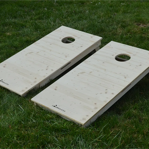 cornhole 2 planches bois naturel, sur le gazon, vue de face